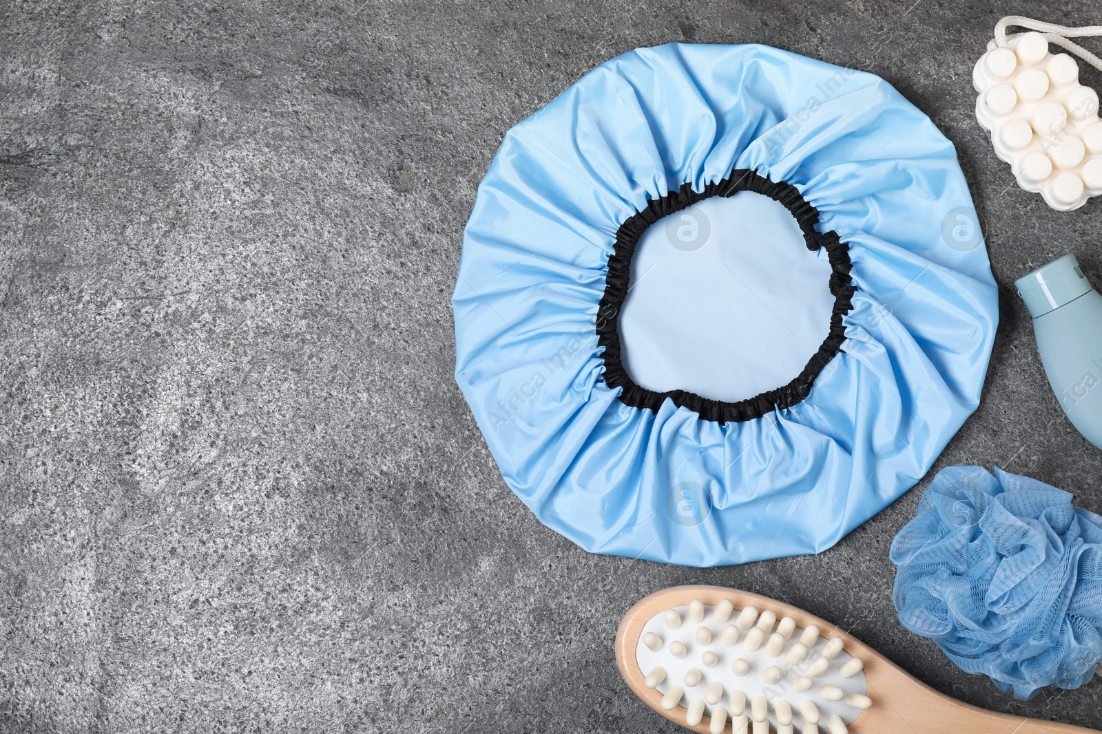 Photo of Shower cap and bath accessories on grey background, flat lay. Space for text