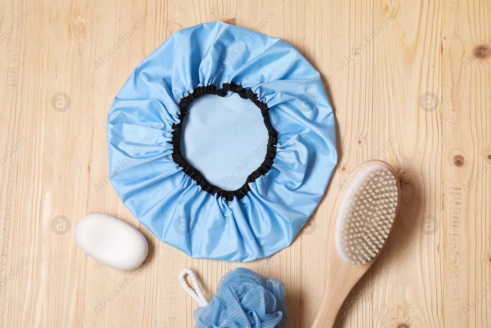 Photo of Shower cap and bath accessories on wooden background, flat lay