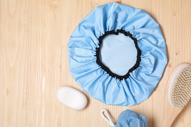 Photo of Shower cap and bath accessories on wooden background, flat lay. Space for text