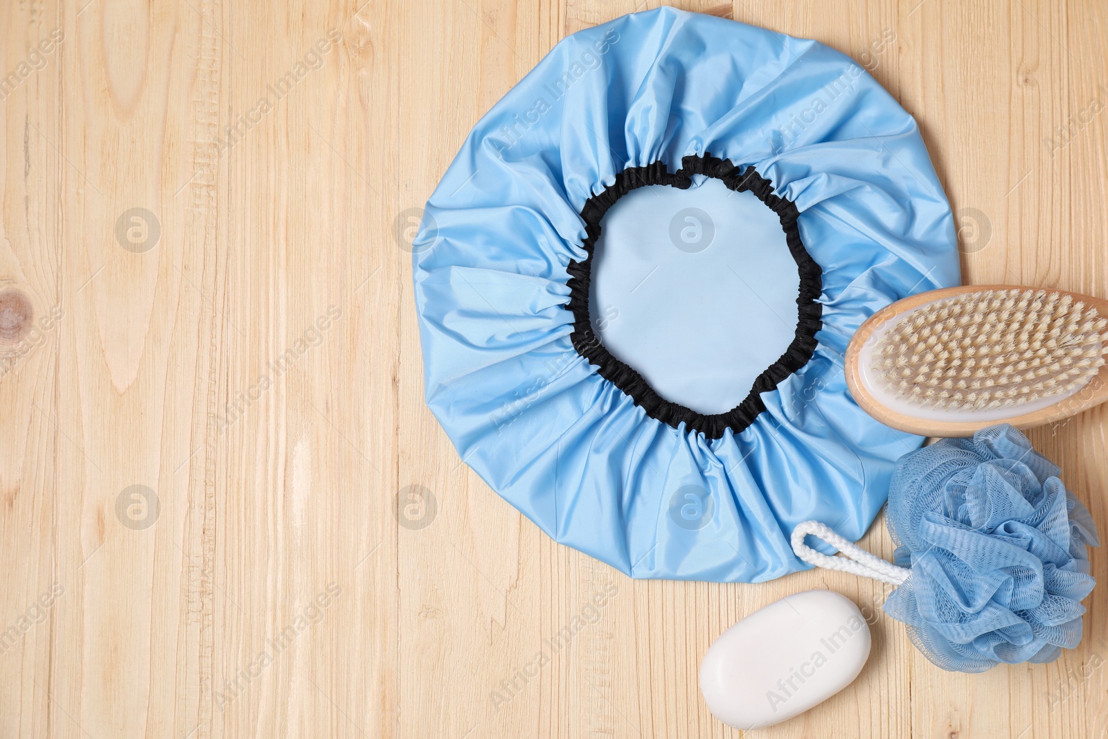 Photo of Shower cap and bath accessories on wooden background, flat lay. Space for text