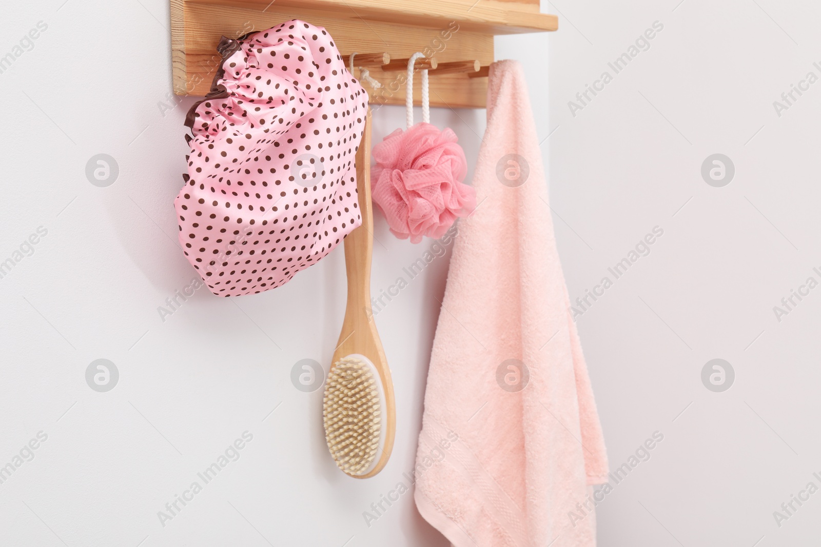 Photo of Shower cap, brush, mesh sponge and towel on rack indoors