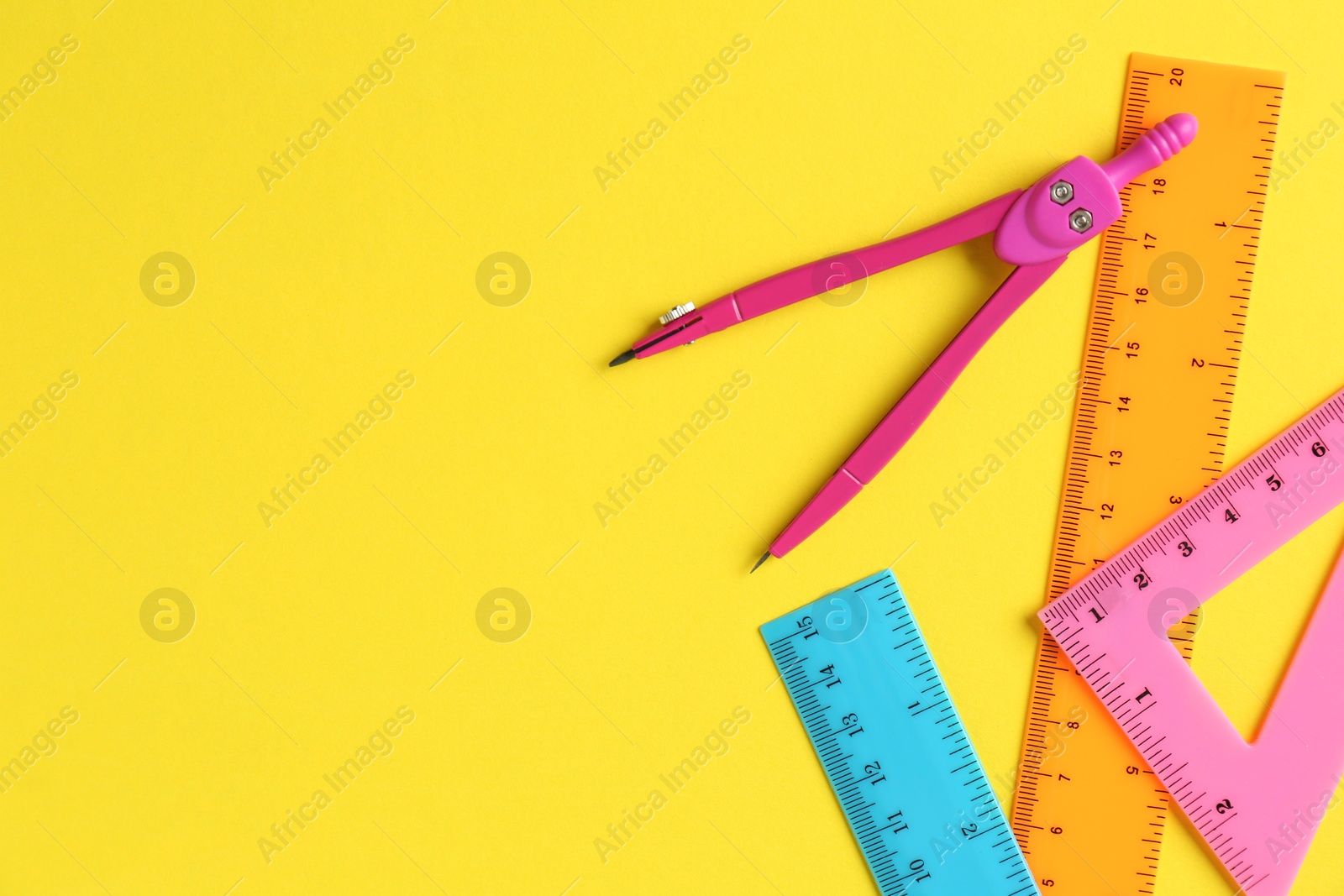 Photo of Rulers and compass on yellow background, flat lay. Space for text