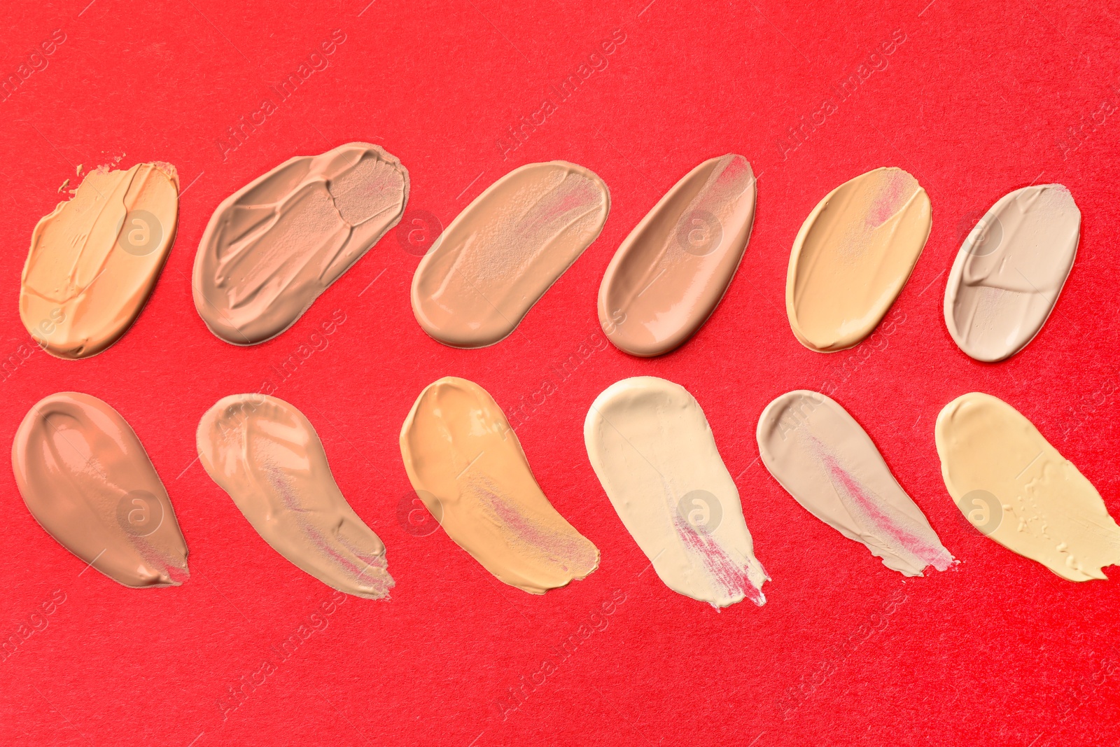 Photo of Samples of different foundations on red background, above view