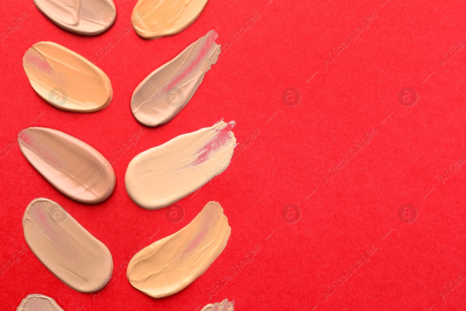 Photo of Samples of different foundations on red background, top view. Space for text