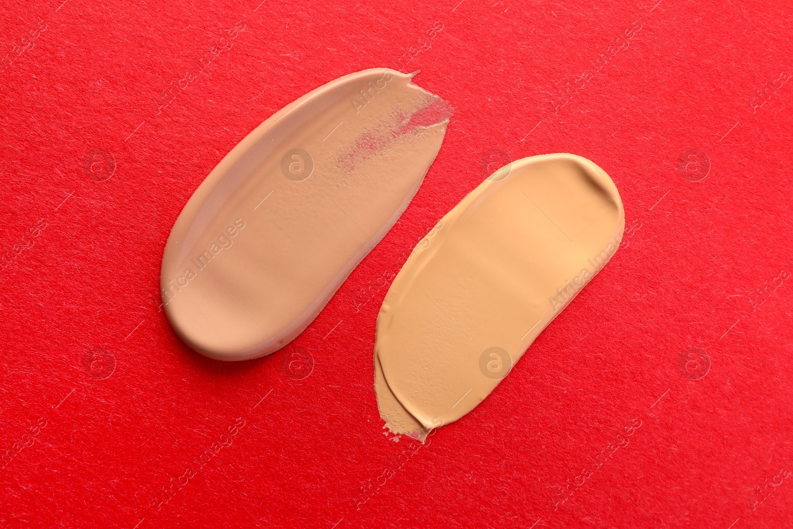 Photo of Samples of different foundations on red background, top view