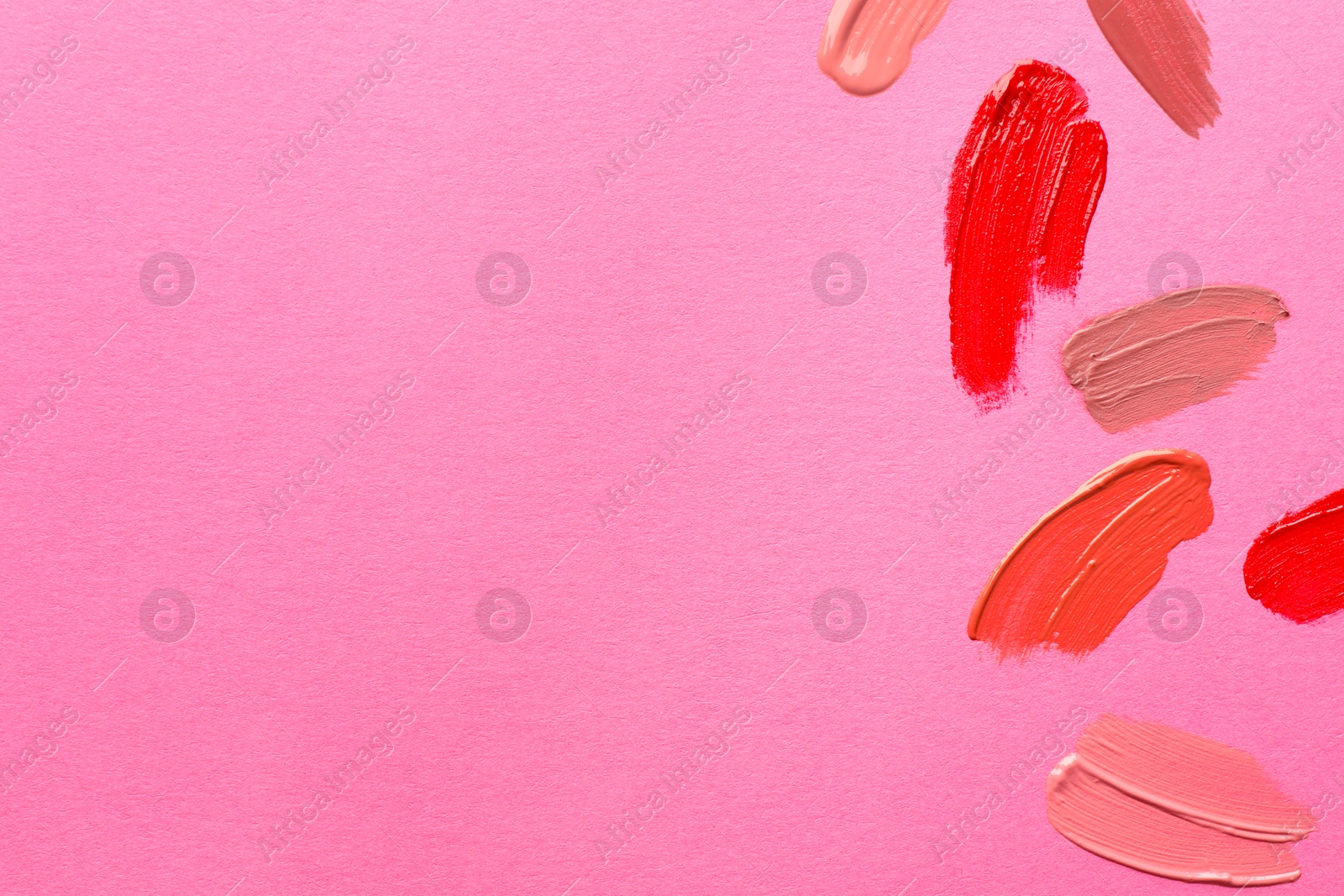 Photo of Samples of different lip products on pink background, top view. Space for text