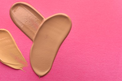 Photo of Foundation on pink background, top view with space for text. Smears of cosmetic product