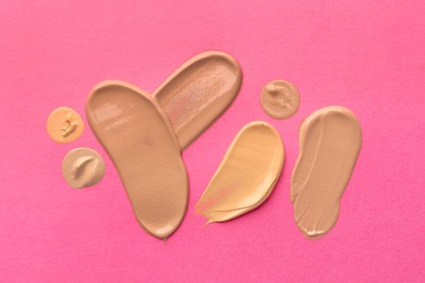 Photo of Foundation on pink background, top view. Smears of cosmetic product