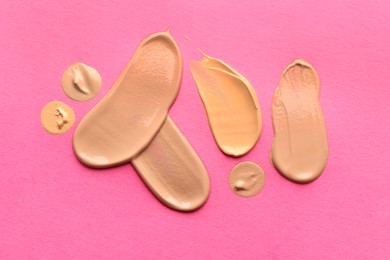 Photo of Foundation on pink background, top view. Smears of cosmetic product