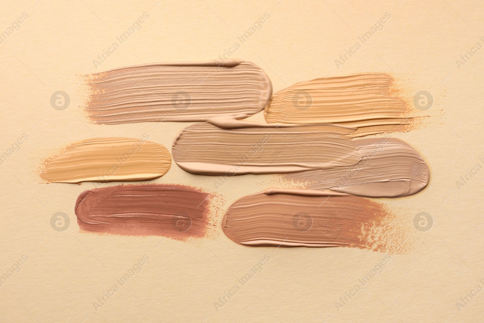 Photo of Samples of different foundations on beige background, top view