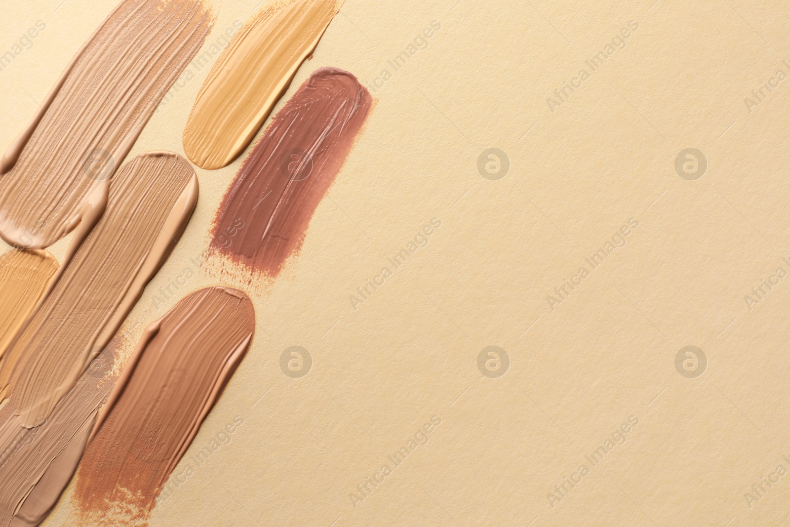 Photo of Samples of different foundations on beige background, top view. Space for text