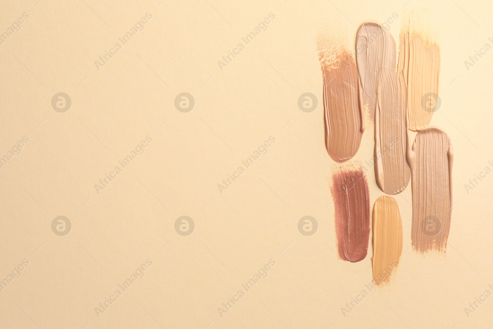 Photo of Samples of different foundations on beige background, top view. Space for text