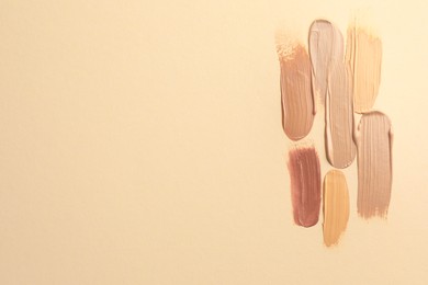 Photo of Samples of different foundations on beige background, top view. Space for text