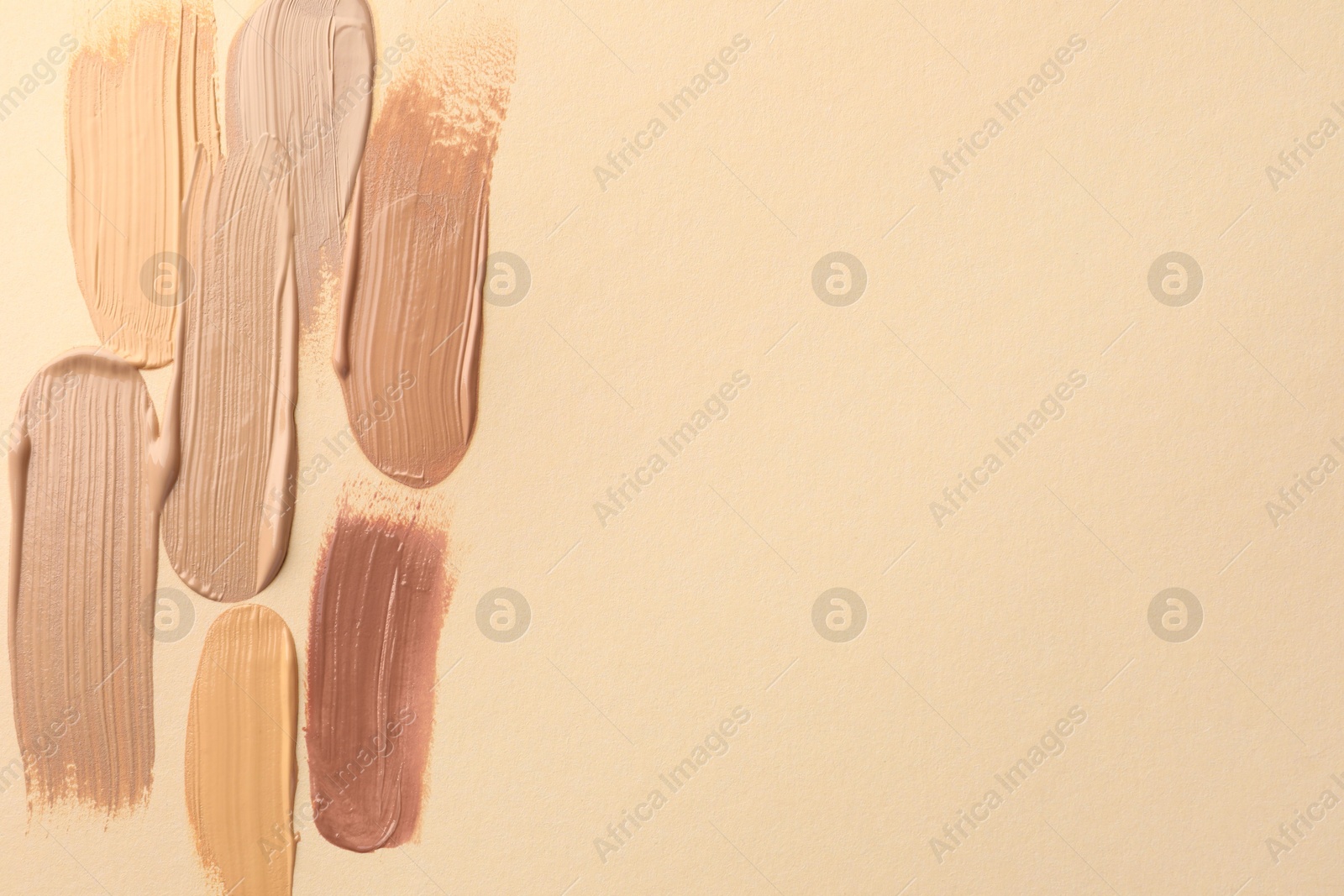 Photo of Samples of different foundations on beige background, top view. Space for text