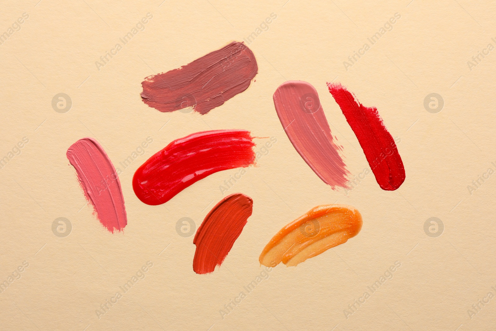 Photo of Samples of different lip products on beige background, top view