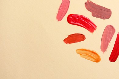 Photo of Samples of different lip products on beige background, top view. Space for text