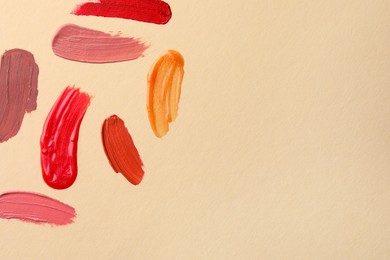 Photo of Samples of different lip products on beige background, top view. Space for text