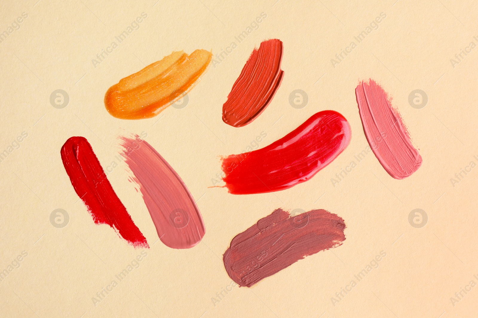 Photo of Samples of different lip products on beige background, top view