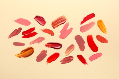 Photo of Samples of different lip products on beige background, top view