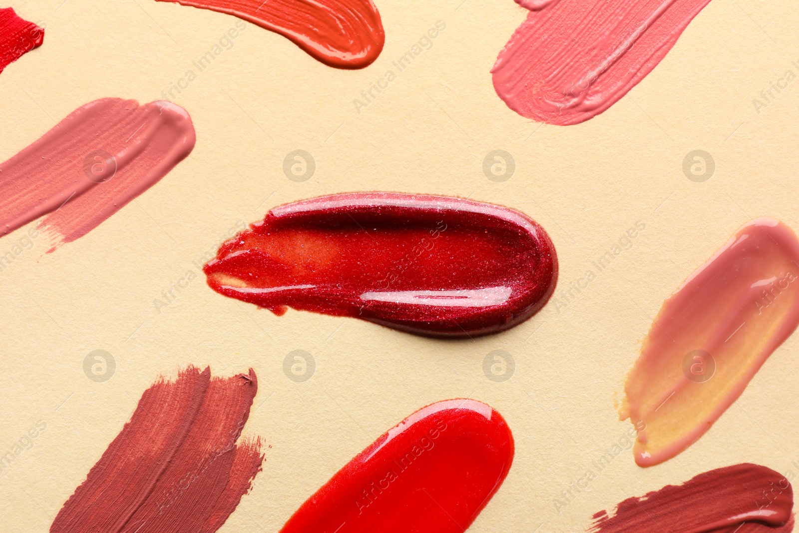 Photo of Samples of different lip products on beige background, top view