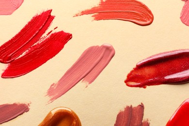 Photo of Samples of different lip products on beige background, top view