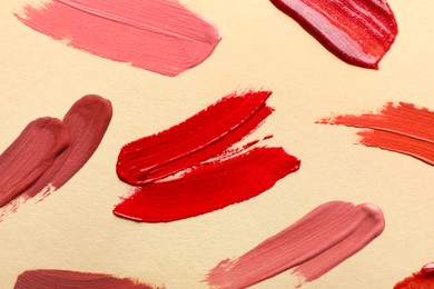 Photo of Samples of different lip products on beige background, top view