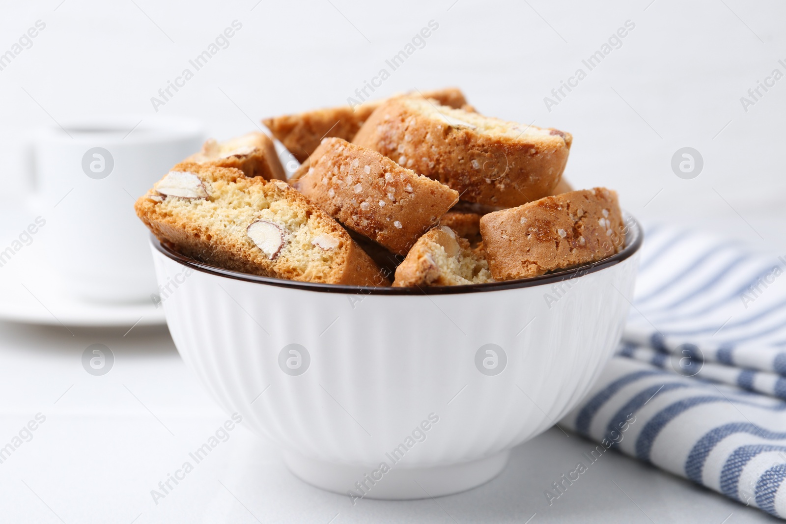 Photo of Traditional Italian almond biscuits (Cantucci) in bowl on white table, closeup