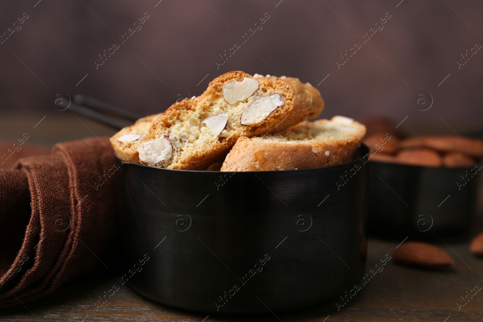 Photo of Tasty almond biscuits (Cantuccini) in scoop on wooden table, closeup