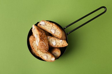 Photo of Tasty almond biscuits (Cantuccini) in scoop on green background, top view