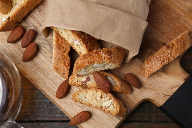 Photo of Paper bag with tasty almond biscuits (Cantuccini) and nuts on wooden table, top view