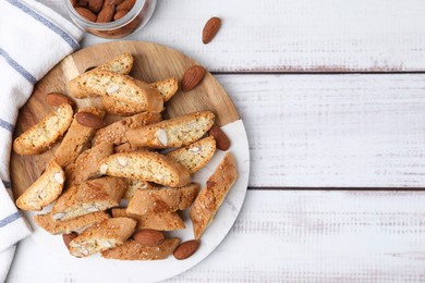 Photo of Tasty almond biscuits (Cantuccini) and nuts on light wooden table, flat lay. Space for text