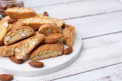 Photo of Tasty almond biscuits (Cantuccini) and nuts on light wooden table, closeup. Space for text