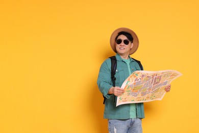 Photo of Traveller with map and backpack on yellow background. Space for text