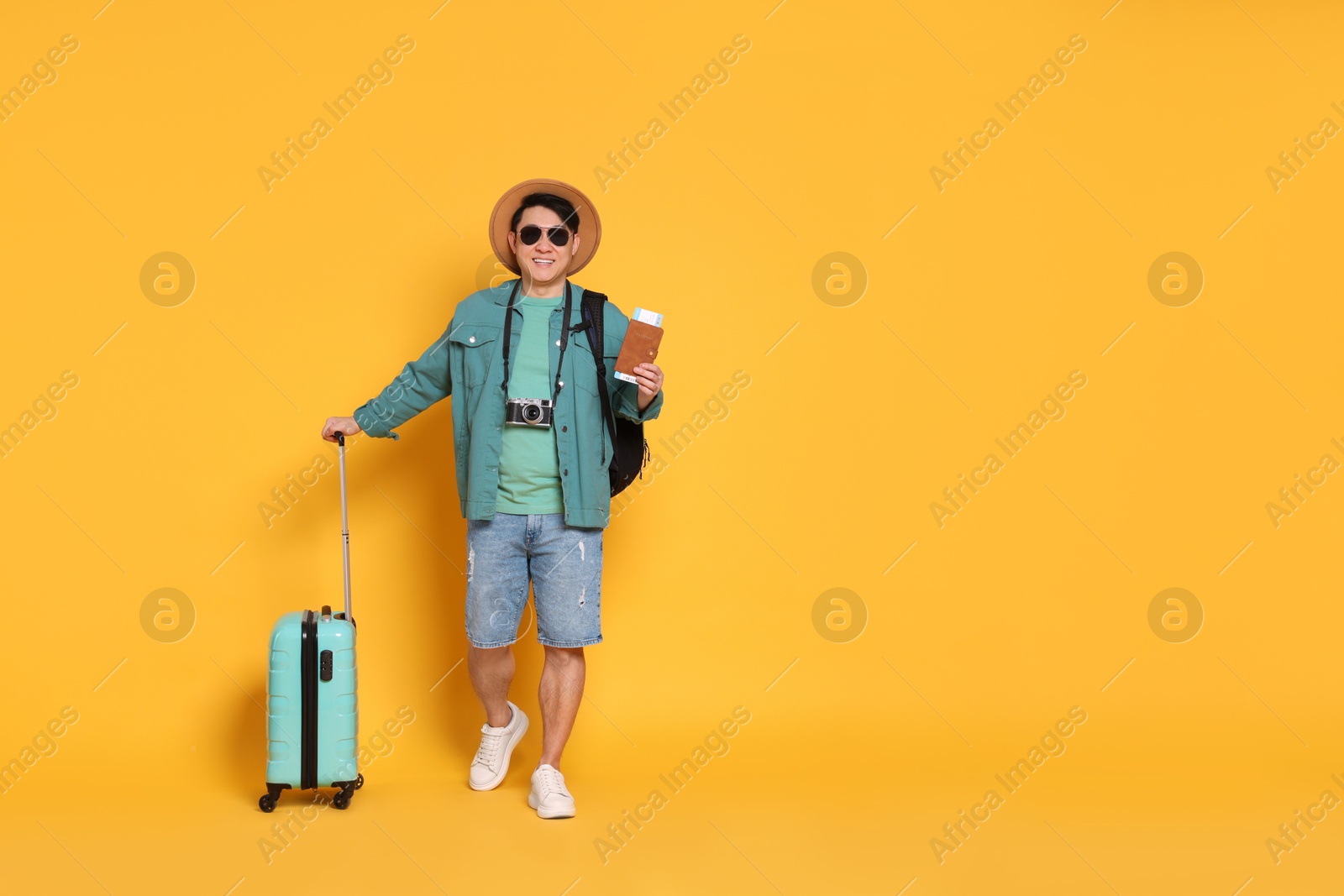 Photo of Traveller with passport and suitcase on yellow background. Space for text