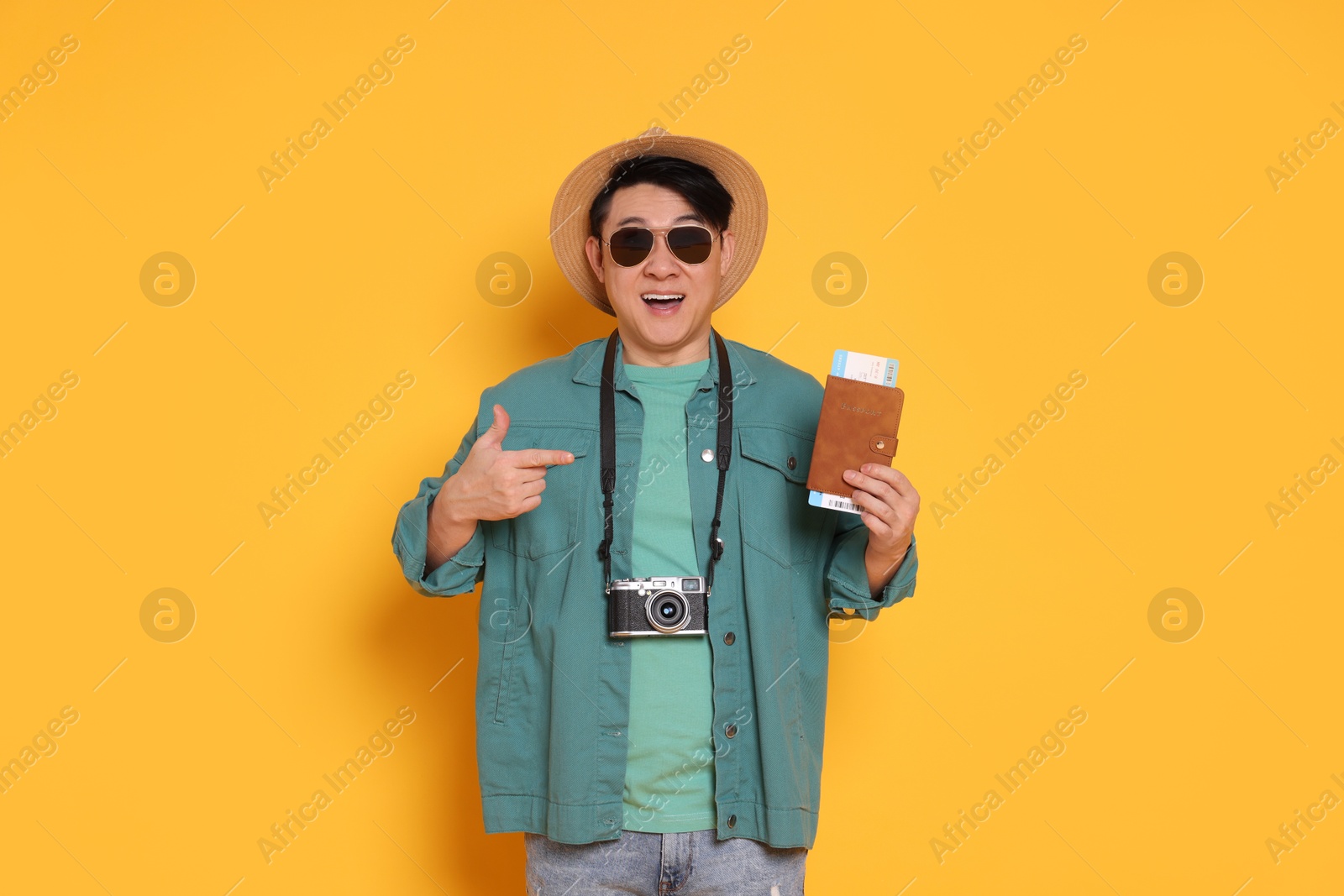 Photo of Happy traveller with passport and camera on yellow background