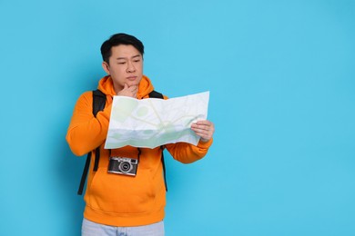 Photo of Pensive traveller with map on light blue background. Space for text