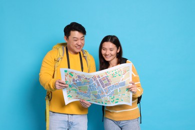 Photo of Happy travellers with map on light blue background