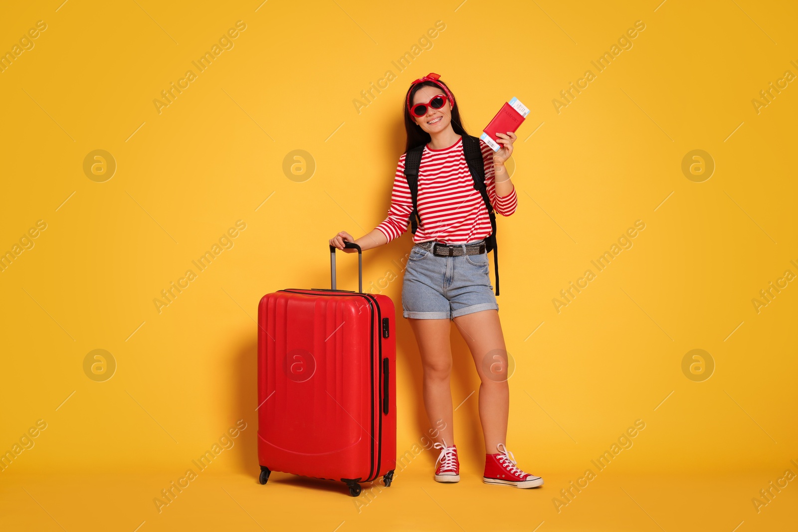 Photo of Traveller with passport and suitcase on yellow background