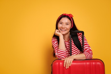 Photo of Happy traveller with suitcase on yellow background. Space for text