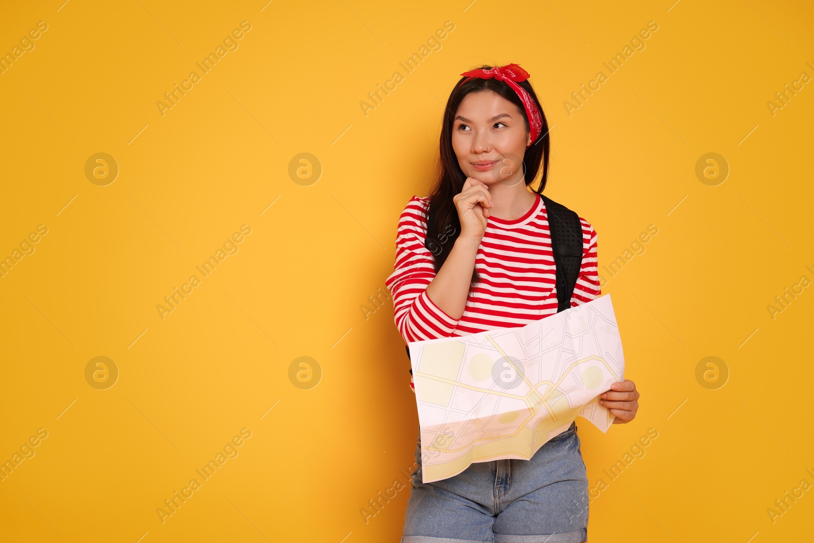 Photo of Pensive traveller with map on yellow background. Space for text