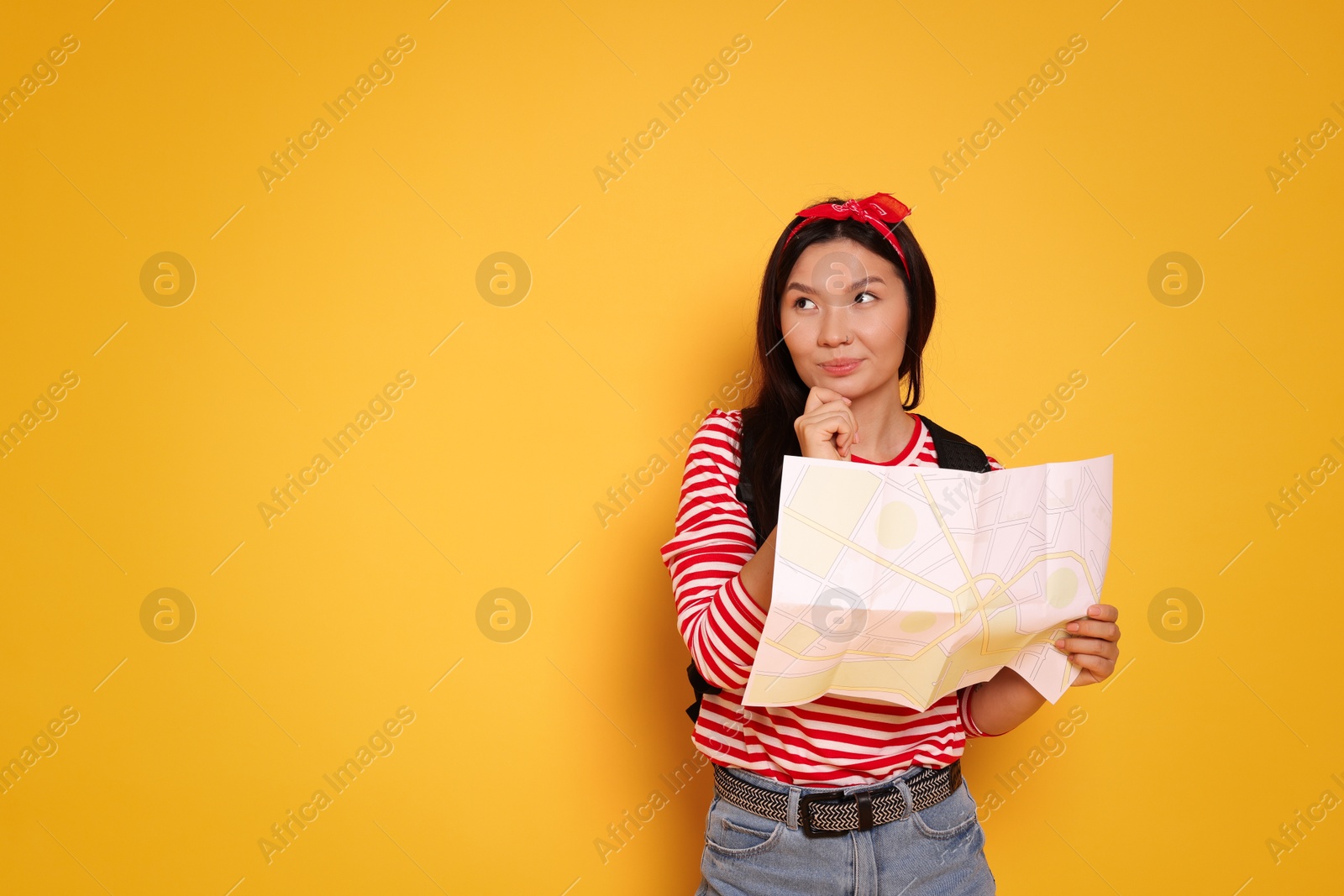 Photo of Pensive traveller with map on yellow background. Space for text