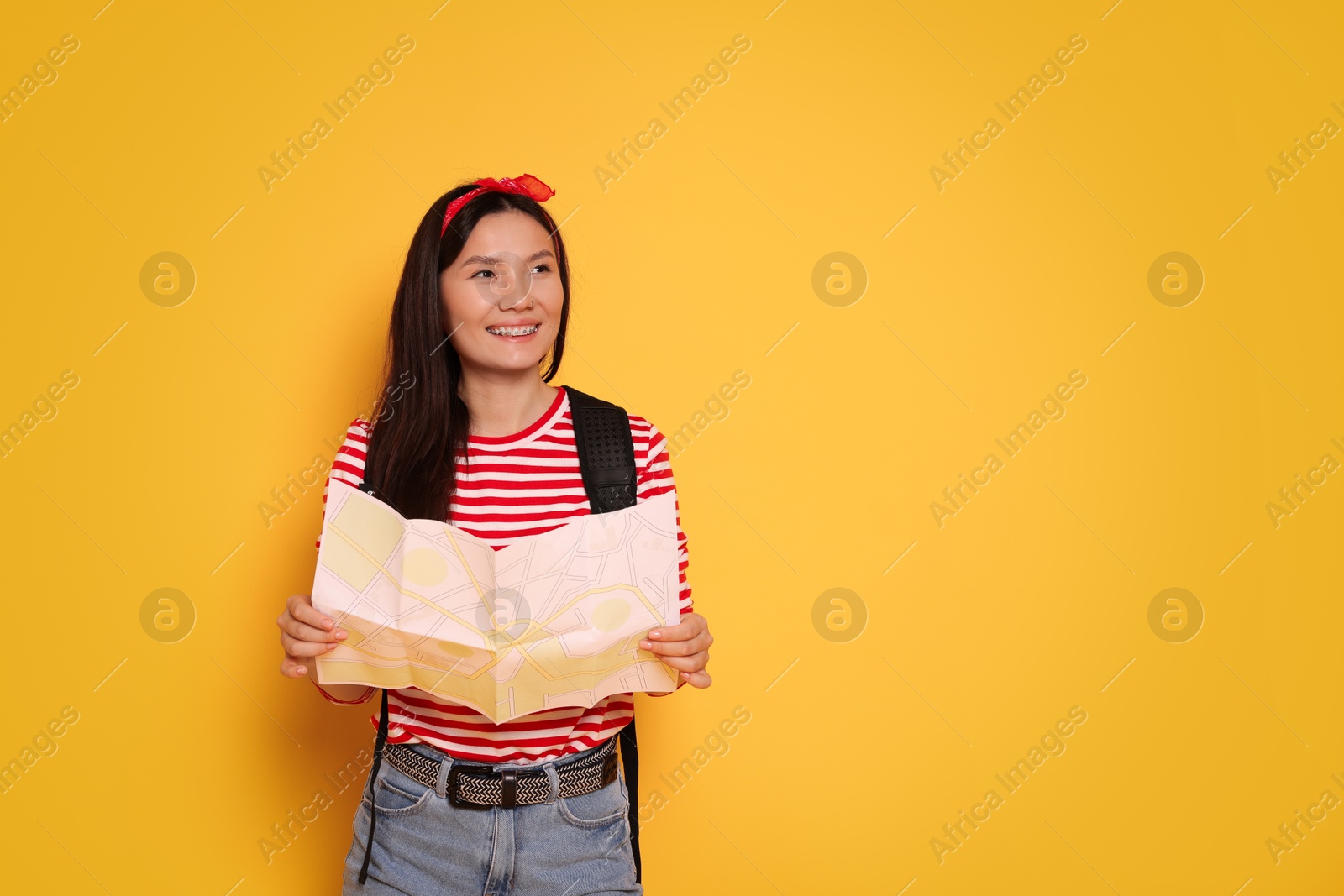 Photo of Happy traveller with map on yellow background. Space for text