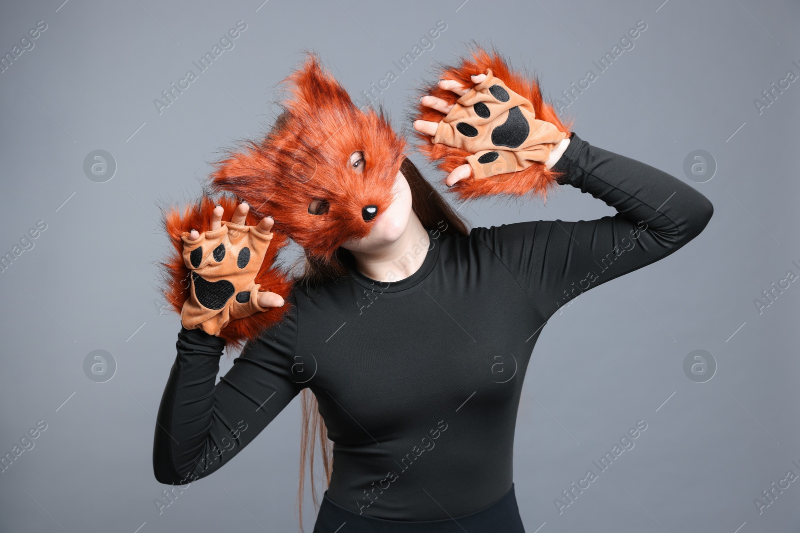 Photo of Quadrobics. Girl wearing fox mask and gloves on grey background