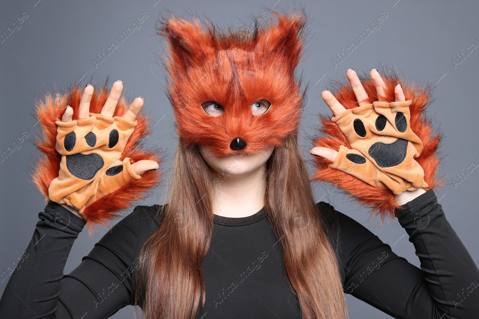 Photo of Quadrobics. Girl wearing fox mask and gloves on grey background