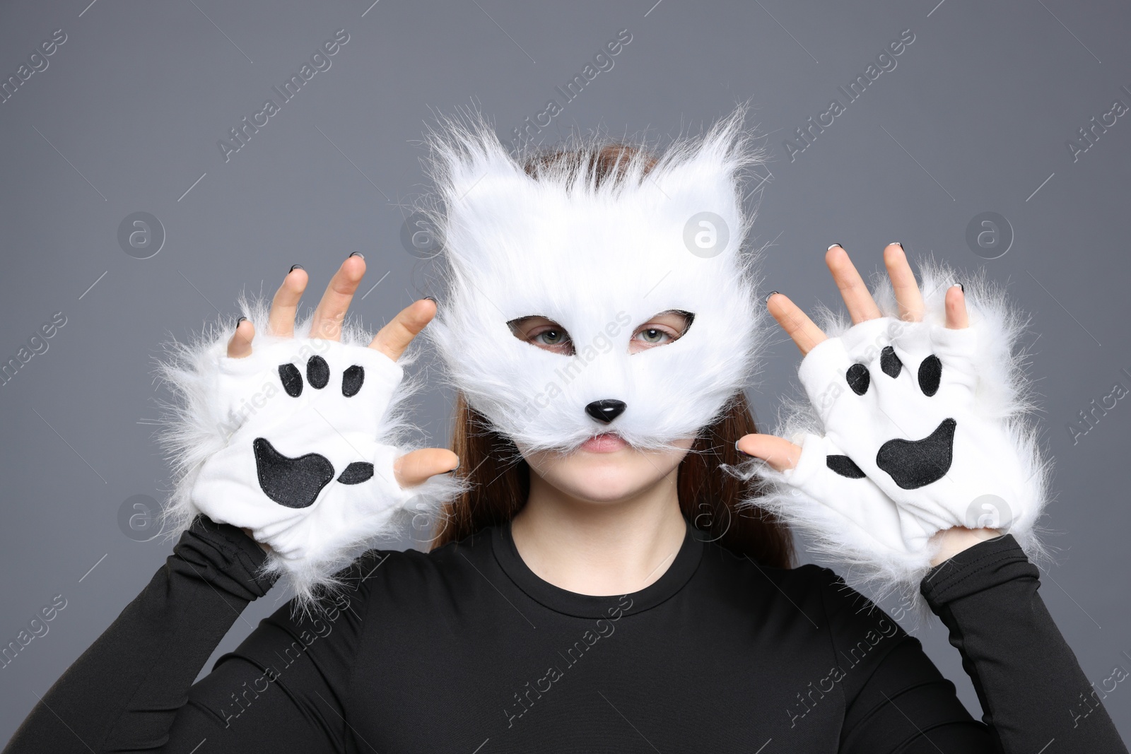 Photo of Quadrobics. Girl wearing cat mask and gloves on grey background