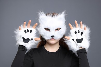 Photo of Quadrobics. Girl wearing cat mask and gloves on grey background