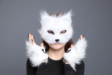 Photo of Quadrobics. Girl wearing cat mask and gloves on grey background