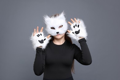 Photo of Quadrobics. Girl wearing cat mask and gloves on grey background