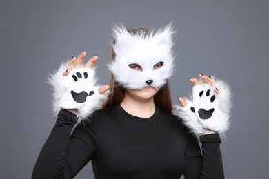 Photo of Quadrobics. Girl wearing cat mask and gloves on grey background