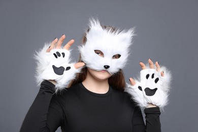 Photo of Quadrobics. Girl wearing cat mask and gloves on grey background